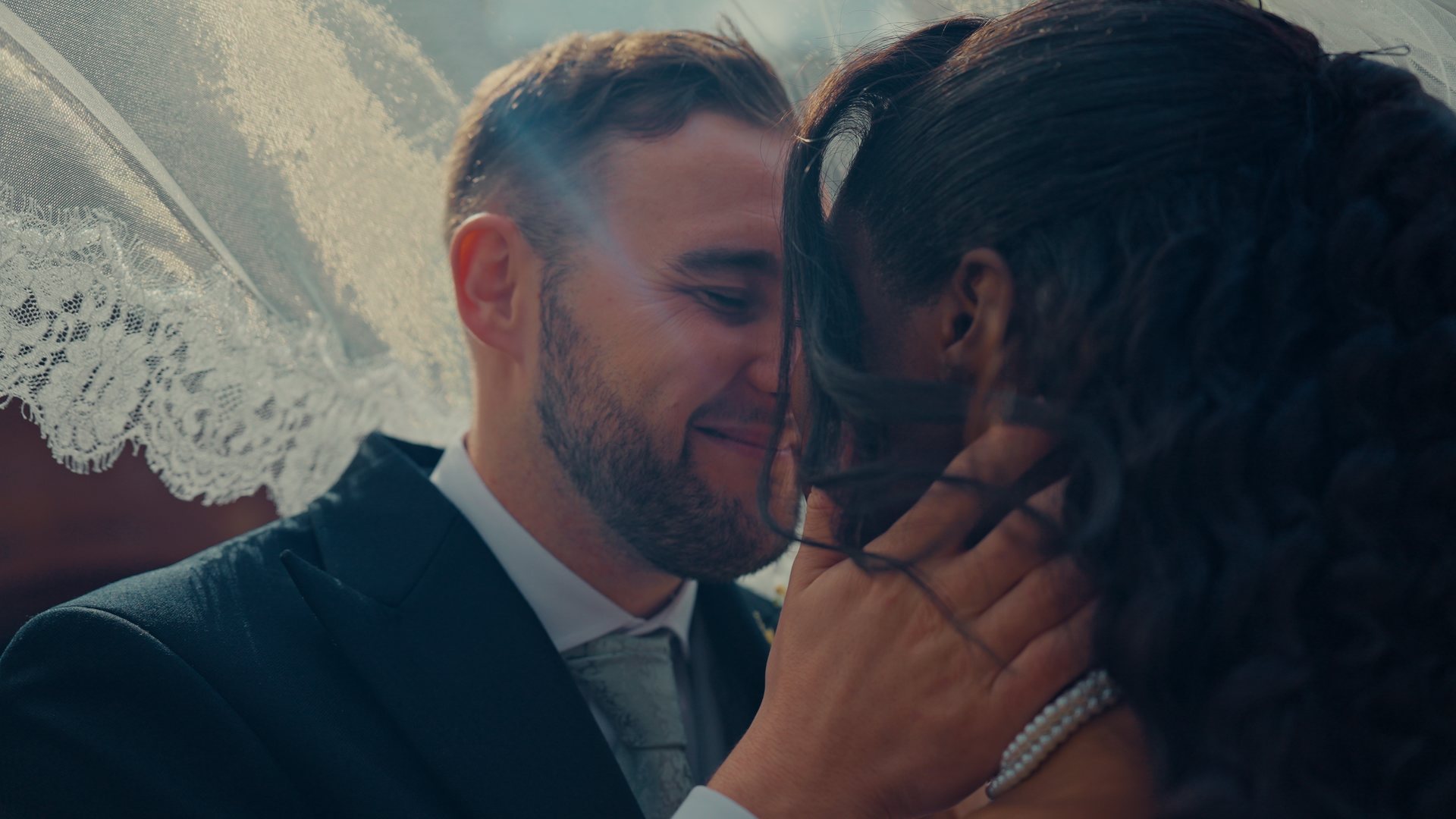 A groom smiling beneath the veil