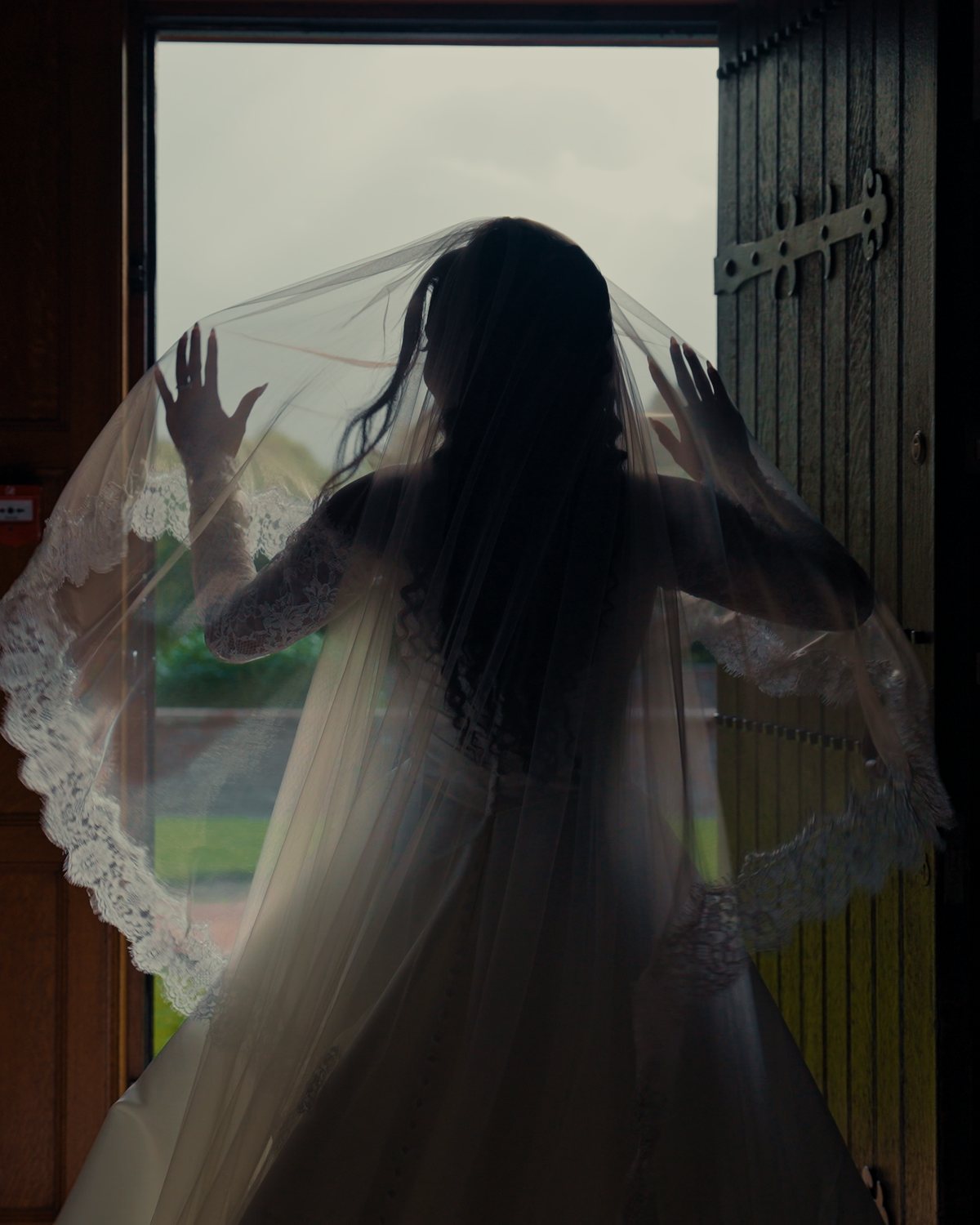 A bride silhouetted in a doorway, holding her veil