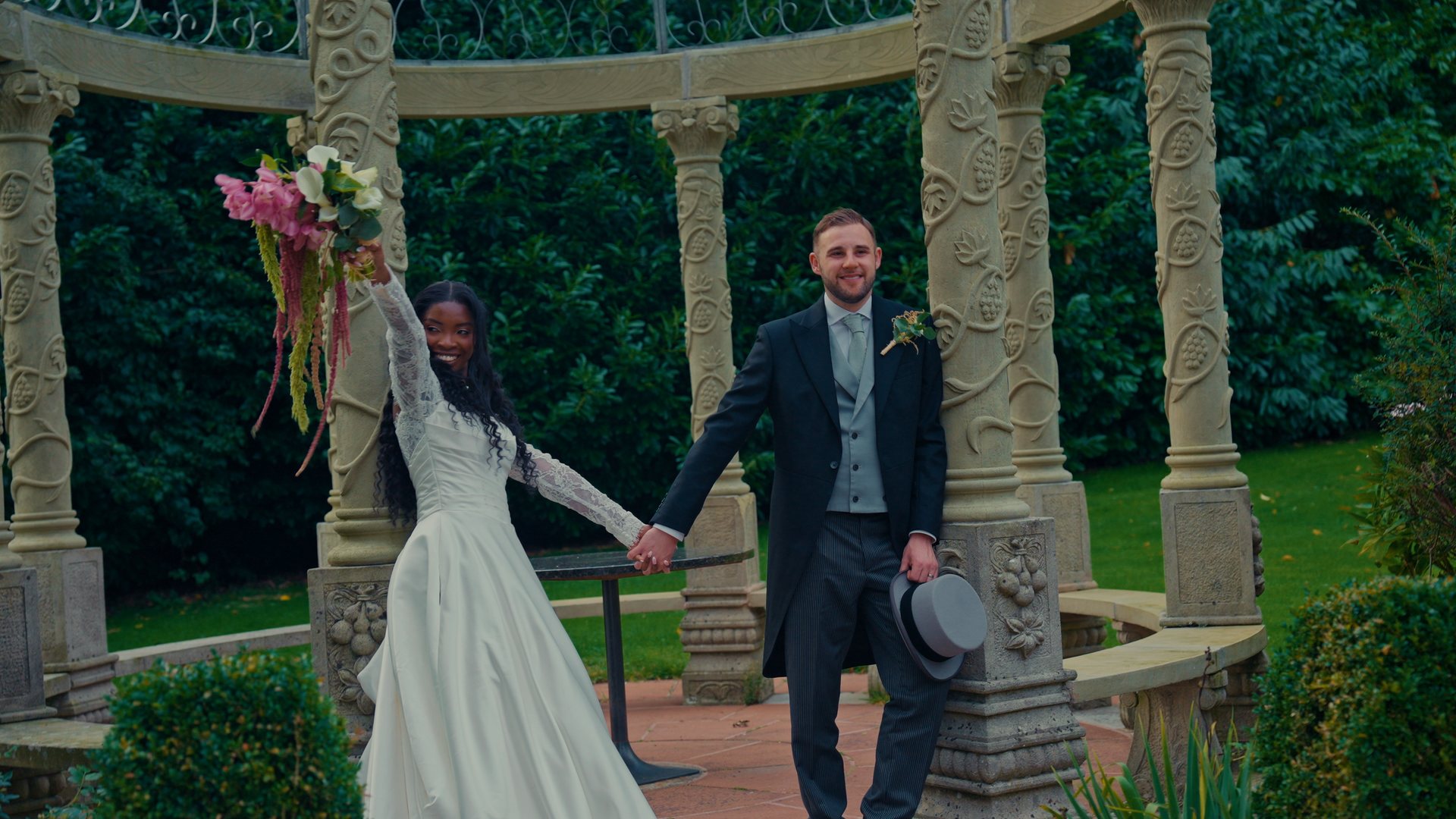 A couple celebrating by a stone gazebo